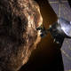 An artist’s depiction of Lucy pasing one of the Trojan asteroids, with Jupiter in the background.